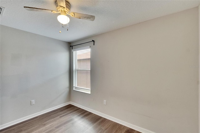 empty room featuring ceiling fan, dark wood-type flooring, and a textured ceiling