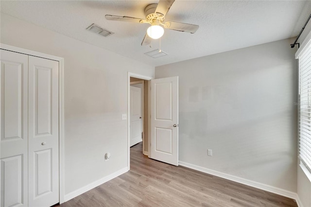 unfurnished bedroom with a textured ceiling, ceiling fan, a closet, and light hardwood / wood-style flooring