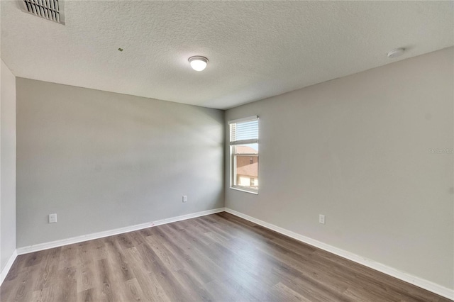 spare room featuring wood-type flooring and a textured ceiling