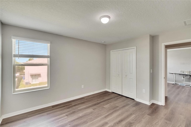 unfurnished bedroom with hardwood / wood-style flooring, a closet, and a textured ceiling