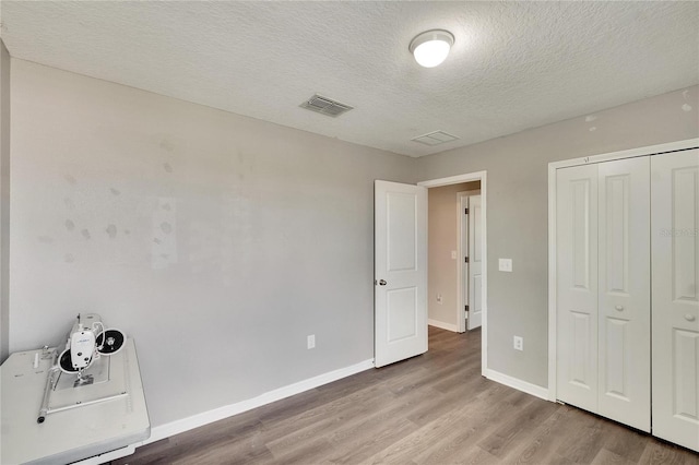 unfurnished bedroom featuring a textured ceiling, a closet, and light hardwood / wood-style floors