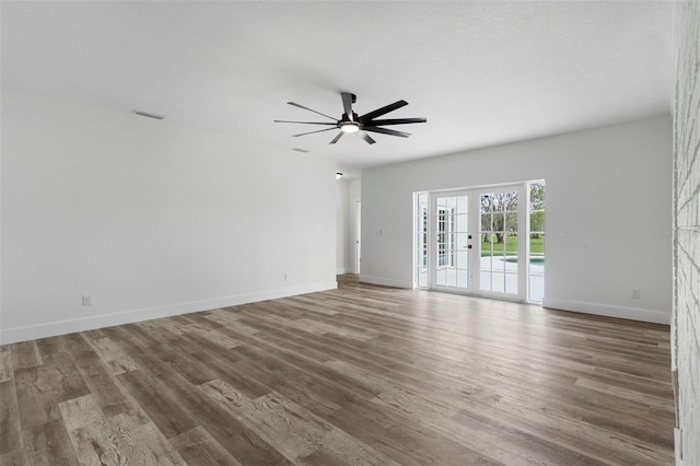 unfurnished room with a textured ceiling, ceiling fan, french doors, and dark hardwood / wood-style flooring