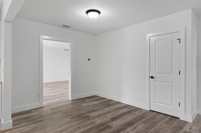 spare room with wood-type flooring and a textured ceiling