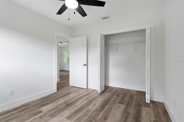 unfurnished bedroom featuring ceiling fan, a closet, and wood-type flooring