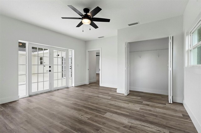 unfurnished bedroom with dark hardwood / wood-style floors, ceiling fan, french doors, and a closet