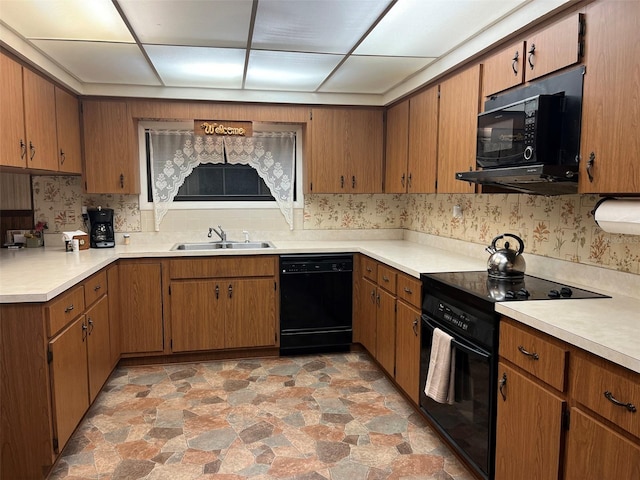 kitchen with a drop ceiling, black appliances, and sink