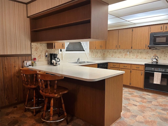 kitchen with black appliances, kitchen peninsula, a breakfast bar area, and sink