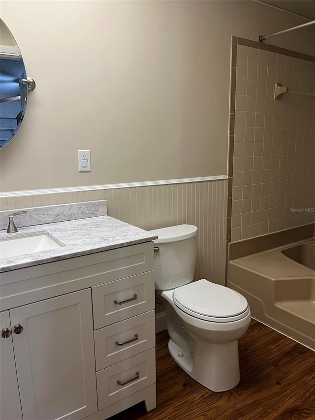 full bathroom featuring tiled shower / bath combo, vanity, hardwood / wood-style floors, and toilet