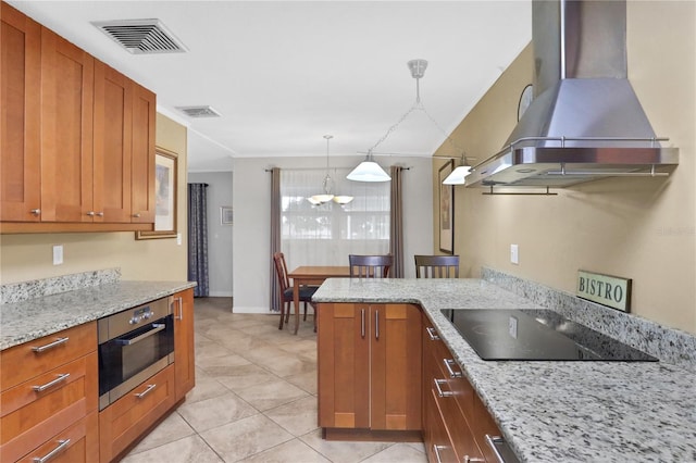 kitchen with hanging light fixtures, light tile patterned floors, wall chimney exhaust hood, black electric cooktop, and light stone countertops