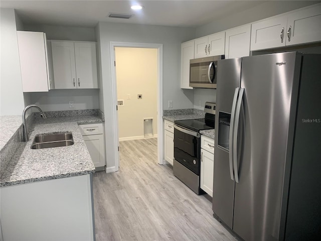 kitchen featuring appliances with stainless steel finishes, light hardwood / wood-style flooring, and white cabinets