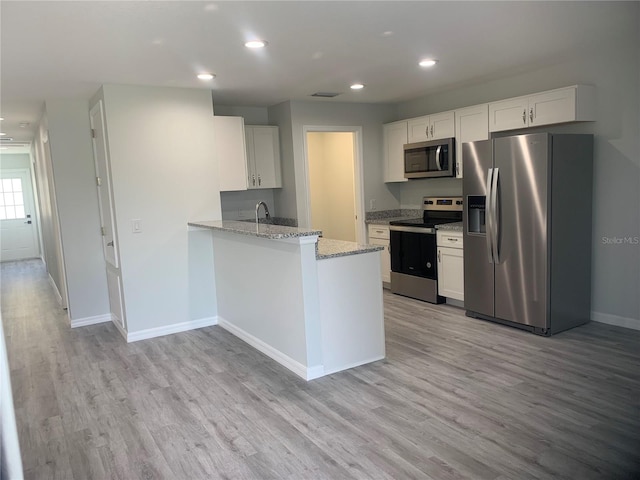 kitchen with light stone countertops, appliances with stainless steel finishes, light hardwood / wood-style flooring, and white cabinets