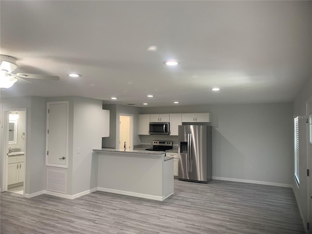 kitchen featuring kitchen peninsula, white cabinetry, light stone countertops, light hardwood / wood-style flooring, and stainless steel appliances