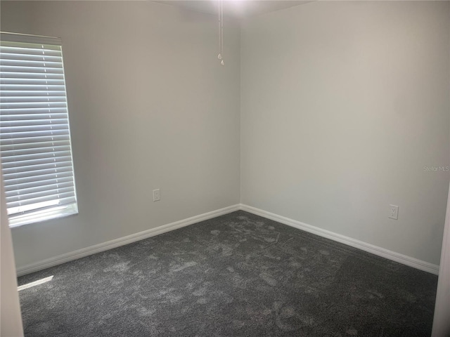 spare room with dark colored carpet