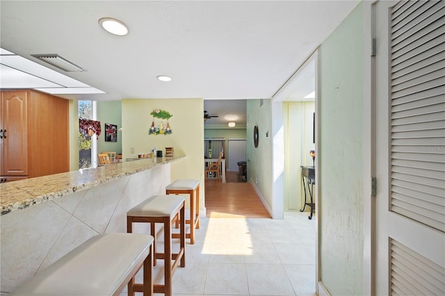 kitchen with light stone counters, a kitchen bar, and light tile patterned flooring