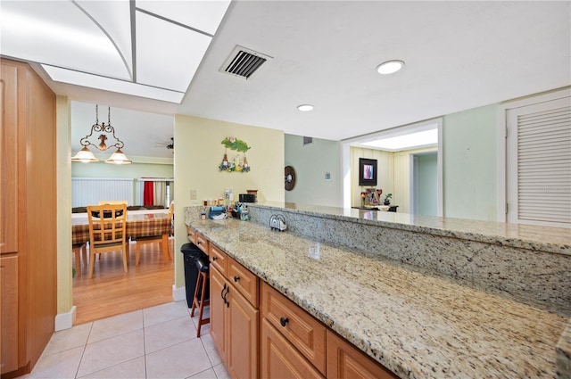 kitchen with light stone countertops, light hardwood / wood-style floors, and hanging light fixtures