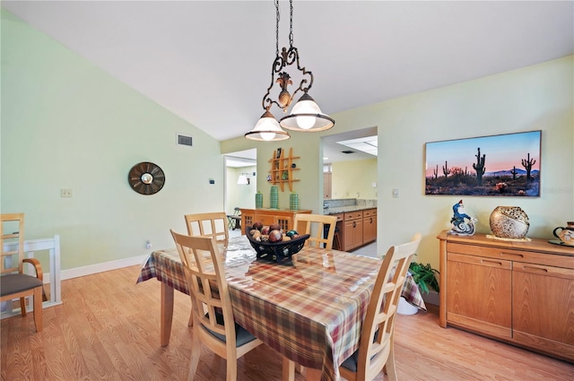 dining room with vaulted ceiling and light hardwood / wood-style flooring