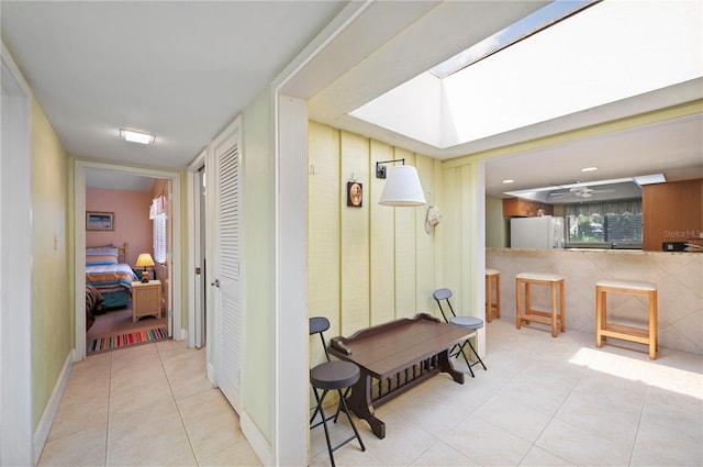 corridor featuring a skylight and light tile patterned floors