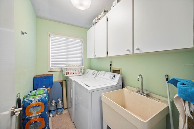 clothes washing area with light carpet, sink, washing machine and clothes dryer, and cabinets