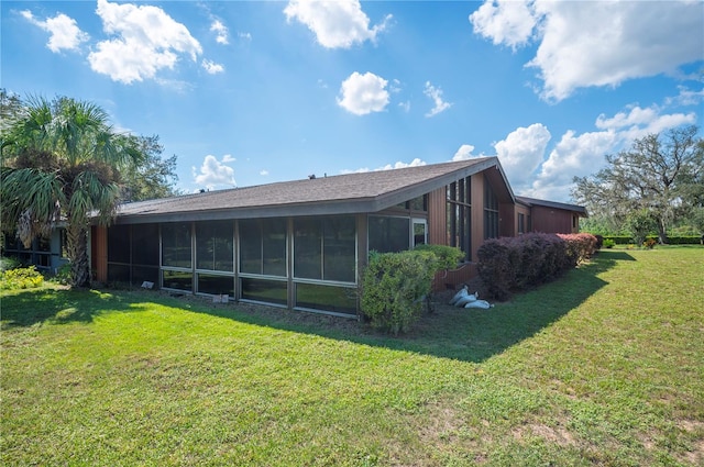 back of property featuring a sunroom and a lawn