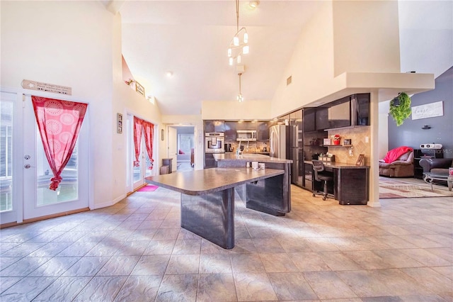 kitchen featuring a kitchen island, a breakfast bar, hanging light fixtures, high vaulted ceiling, and appliances with stainless steel finishes