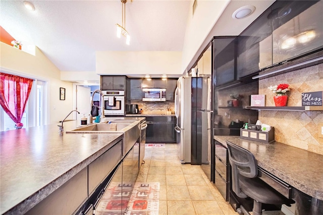 kitchen featuring backsplash, appliances with stainless steel finishes, hanging light fixtures, and vaulted ceiling