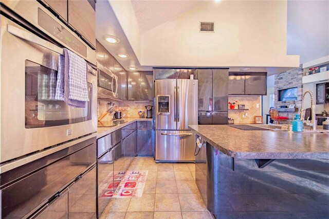 34415 Kingfish St, Fruitland Park, FL 34731 - kitchen with appliances with stainless steel finishes, lofted ceiling, decorative backsplash, light tile patterned flooring, and dark countertops