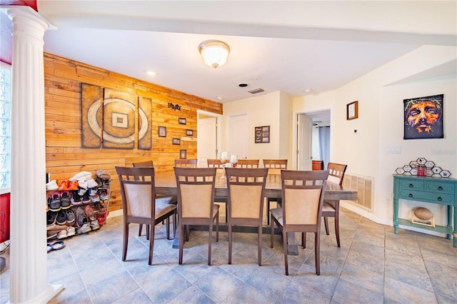 dining room featuring decorative columns and wooden walls