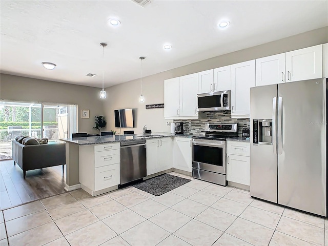 kitchen featuring stainless steel appliances, white cabinetry, kitchen peninsula, and hanging light fixtures