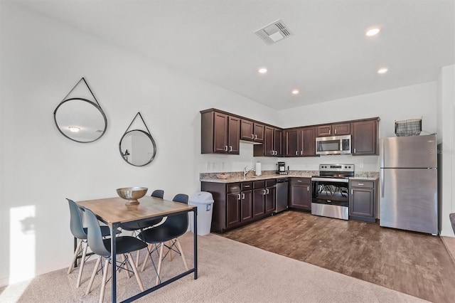 kitchen with dark brown cabinetry, appliances with stainless steel finishes, carpet flooring, and sink