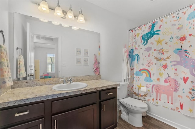 full bathroom with shower / bath combo with shower curtain, hardwood / wood-style flooring, vanity, and toilet