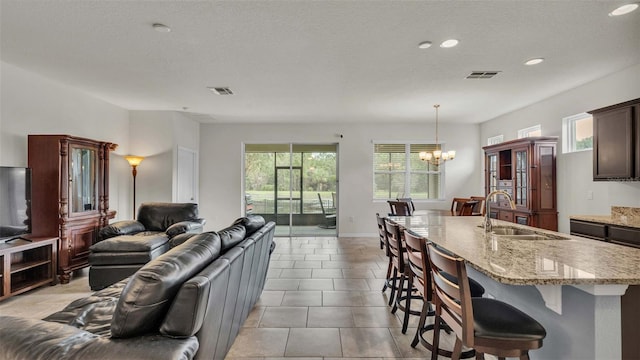 tiled living room featuring a textured ceiling, sink, a wealth of natural light, and a chandelier