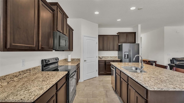 kitchen with appliances with stainless steel finishes, dark brown cabinets, a textured ceiling, sink, and a center island with sink