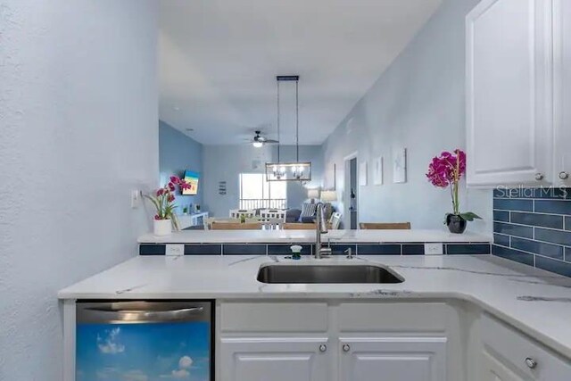 kitchen with dishwasher, tasteful backsplash, sink, white cabinets, and decorative light fixtures