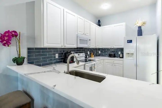 kitchen with light stone counters, sink, white cabinets, white appliances, and backsplash