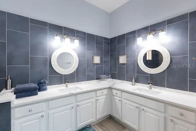 bathroom with wood-type flooring, vanity, tile walls, and backsplash