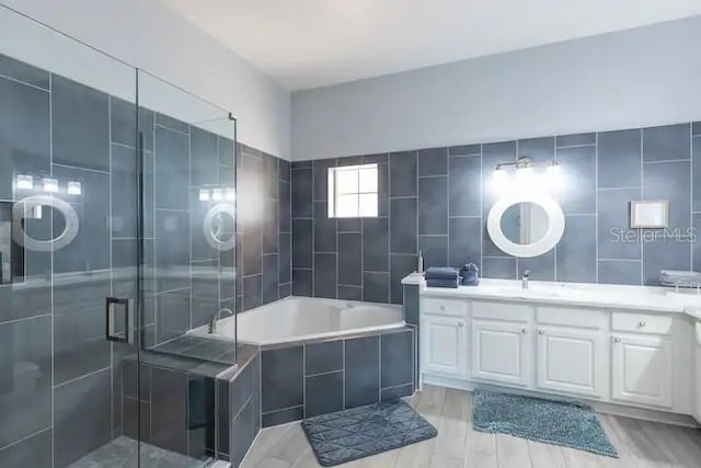 bathroom with independent shower and bath, vanity, and tile walls