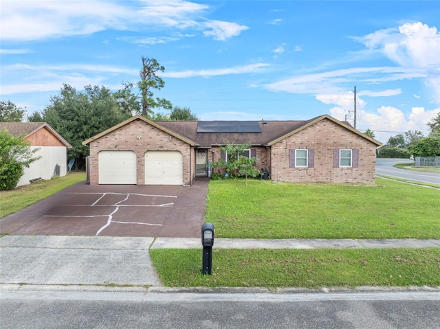 ranch-style house featuring solar panels, a garage, and a front yard