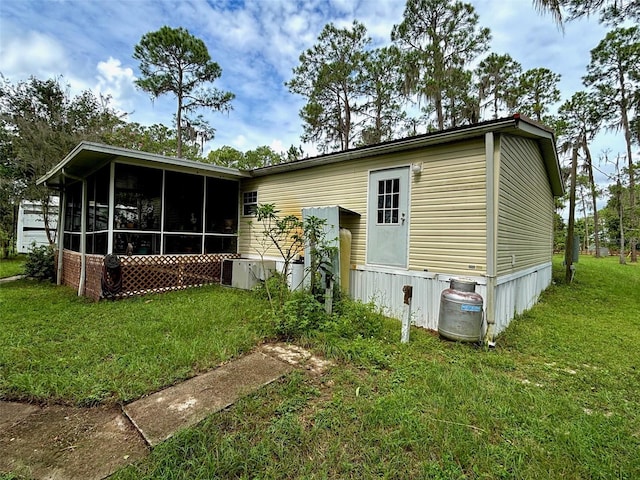 rear view of property featuring a yard, a sunroom, and cooling unit