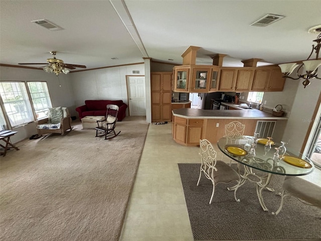 kitchen with a healthy amount of sunlight, vaulted ceiling, kitchen peninsula, and ceiling fan with notable chandelier