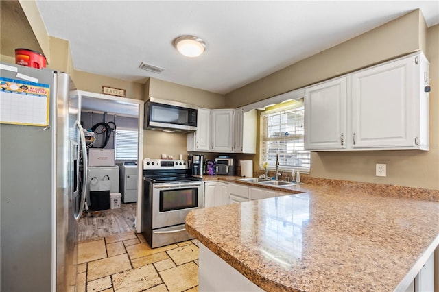 kitchen featuring kitchen peninsula, washer and dryer, white cabinetry, and stainless steel appliances