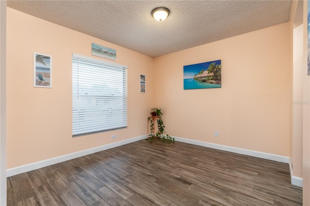 empty room featuring a textured ceiling and dark wood-type flooring