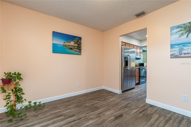 spare room featuring dark wood-type flooring and a textured ceiling