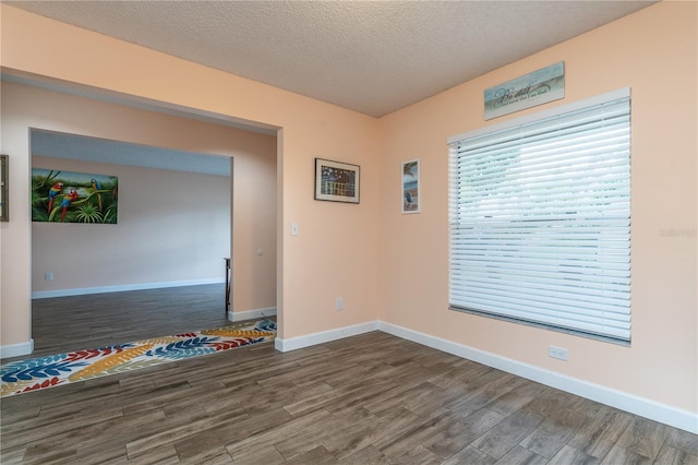 unfurnished room with a textured ceiling and dark hardwood / wood-style flooring