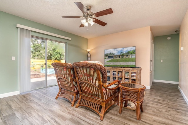 sitting room with light hardwood / wood-style flooring, a textured ceiling, and ceiling fan