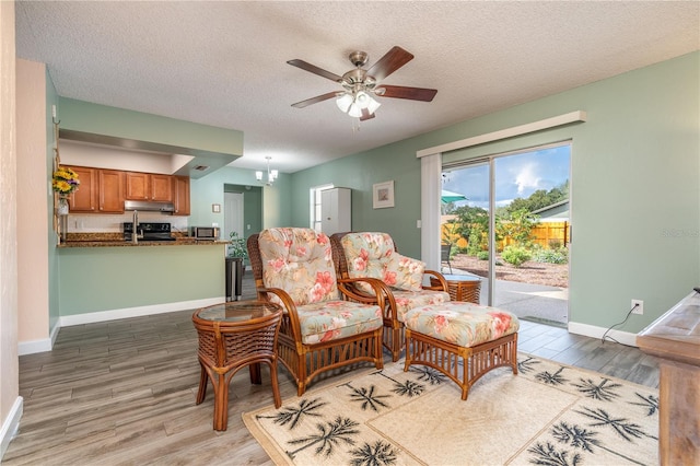 living room featuring light hardwood / wood-style floors, a textured ceiling, and ceiling fan