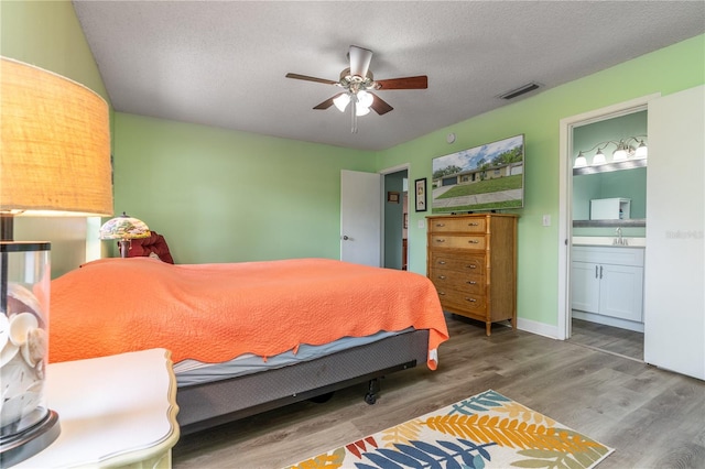 bedroom featuring ceiling fan, a textured ceiling, connected bathroom, dark hardwood / wood-style floors, and sink