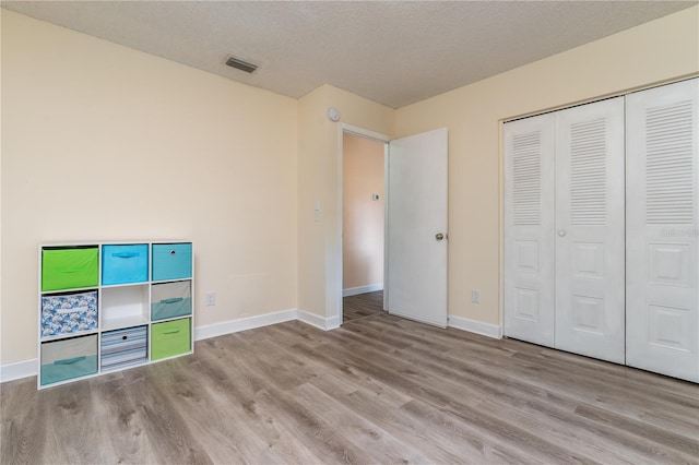 unfurnished bedroom with light hardwood / wood-style floors, a textured ceiling, and a closet