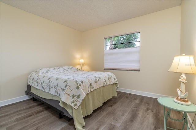 bedroom with a textured ceiling and dark hardwood / wood-style floors