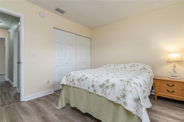 bedroom with a closet, a textured ceiling, and hardwood / wood-style flooring