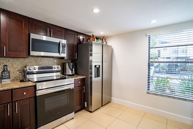 kitchen featuring appliances with stainless steel finishes, decorative backsplash, light stone counters, and plenty of natural light